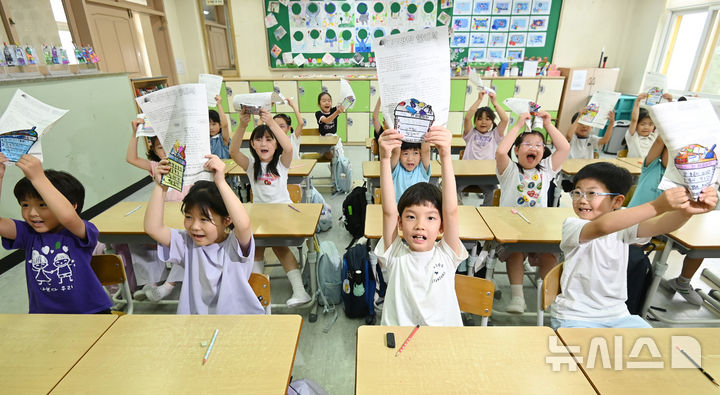 [수원=뉴시스] 김종택 기자 = 여름방학식이 열린 27일 경기 수원시 장안구 효천초등학교에서 1학년1반 학생들이 방학안내문을 들어보이고 있다. 2026.07.27. jtk@newsis.com
