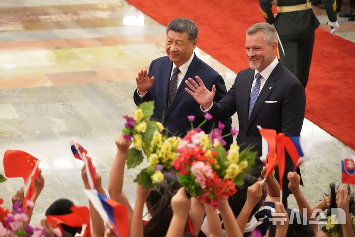 [베이징=AP/뉴시스] 시진핑(왼쪽) 중국 국가주석과 페테르 펠레그리니 슬로바키아 대통령이 28일(현지 시간) 중국 베이징 인민대회당에서 열린 환영식에서 어린이들을 향해 손을 흔들고 있다. 2026.07.28.