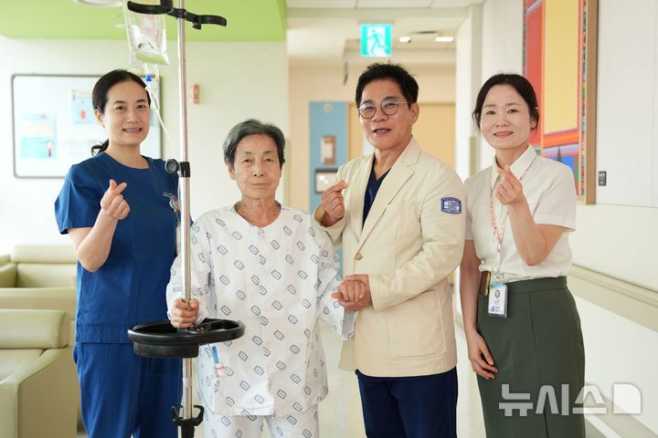 [서울=뉴시스] 장기육 서울성모병원 교수(환자 옆 오른쪽)와 의료진이 6년전 시술 받은 타비판막의 퇴행성 변화로 중증 대동맥판막으로 진행된 89세 환자를 차세대 TAVI 재시술로 치료하고 건강을 기원하며 기념사진을 촬영했다. (사진= 서울성모병원 제공)