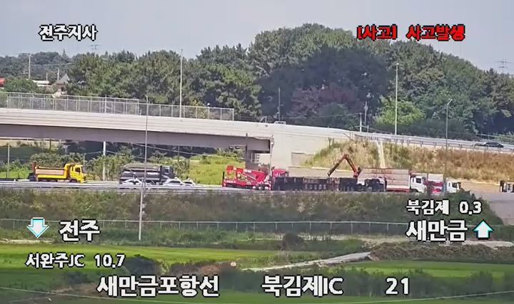 [김제=뉴시스] 29일 오전 8시49분께 전북 김제시 상정로를 지나는 국도 23호선에서 달리던 트레일러 차량이 우측으로 전도돼 적재물이 쏟아지자 정리 작업이 진행되고 있다. (사진=도시교통정보센터 CCTV 화면 갈무리) 2026.07.29. photo@newsis.com *재판매 및 DB 금지