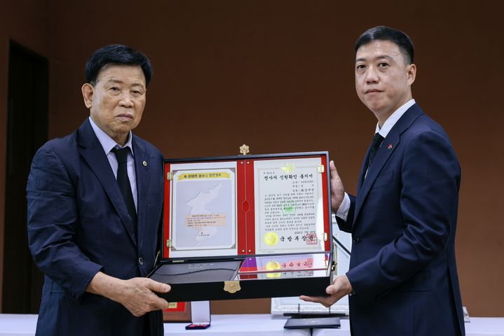 [서울=뉴시스] 29일 오전 전남 광양시에서 열린 고 강대언 경사 ‘호국의 영웅 귀환 행사’에서 김성환 국방부 유해발굴감식단장 직무대리가 고인의 동생 강대유 씨(83)에게 호국의 얼 함을 전달하고 있다. (사진=국방부 제공) 2026.07.29. photo@newsis.com *재판매 및 DB 금지