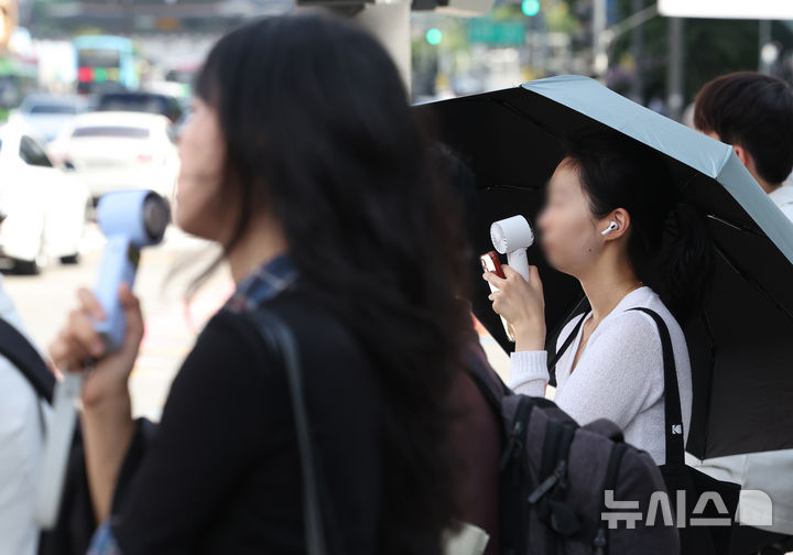 [서울=뉴시스] 김명년 기자 = 무더위가 이어진 29일 서울 중구 세종대로 사거리에서 시민들이 휴대용 선풍기를 사용하며 출근하고 있다. 2026.07.29. kmn@newsis.com