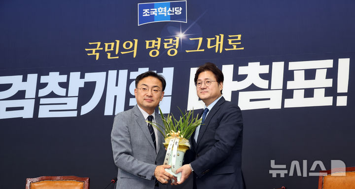 [서울=뉴시스] 최진석 기자 = 신장식(왼쪽) 조국혁신당 대표가 29일 여의도 국회에서 홍익표 청와대 정무수석과 접견며 이재명 대통령이 보낸 축하난을 받고 있다. 2026.07.29. myjs@newsis.com