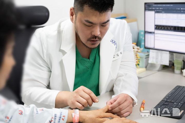 [서울=뉴시스] 김철 연세사랑병원 원장이 환자의 손을 확인하고 있다. (사진= 연세사랑병원 제공)