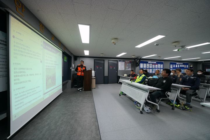 [서울=뉴시스] 롯데건설 안전관리자가 한 아파트 공사 현장에서 AI 근로자 다국어 번역 모델을 활용해 외국인 근로자들을 대상으로 안전교육을 진행하고 있다. (사진=롯데 제공) *재판매 및 DB 금지