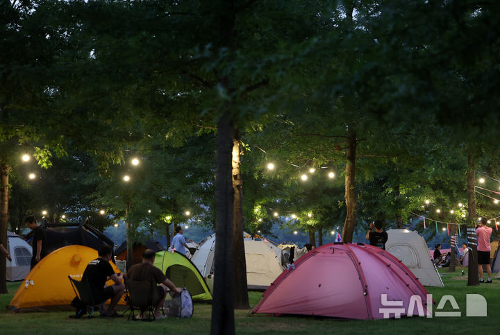 [서울=뉴시스] 이영환 기자 = 1일 오후 서울 영등포구 여의도한강공원 물빛무대 앞 잔디밭에서 운영되는 임시 야영장 한강 밤핑(Night+Camping)을 찾은 시민들이 즐거운 시간을 보내고 있다. 서울시는 휴가철을 맞아 8월 한 달간 여의도·뚝섬 한강공원에서 임시 야영장인 '한강 밤핑(Night+Camping)'을 운영한다. 여의도 한강공원 물빛무대 앞 잔디밭과 뚝섬 한강공원 한강플플 잔디밭에 각각 텐트 100동씩 총 200동 규모 야영장을 조성한다. 운영 시간은 매일 오후 5시부터 다음날 오전 9시까지다. 2026.08.01. 20hwan@newsis.com