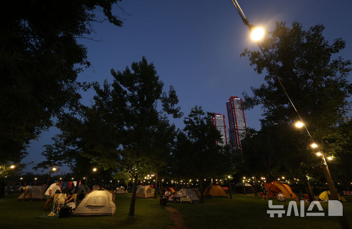 [서울=뉴시스] 이영환 기자 = 1일 오후 서울 영등포구 여의도한강공원 물빛무대 앞 잔디밭에서 운영되는 임시 야영장 한강 밤핑(Night+Camping)을 찾은 시민들이 즐거운 시간을 보내고 있다. 서울시는 휴가철을 맞아 8월 한 달간 여의도·뚝섬 한강공원에서 임시 야영장인 '한강 밤핑(Night+Camping)'을 운영한다. 여의도 한강공원 물빛무대 앞 잔디밭과 뚝섬 한강공원 한강플플 잔디밭에 각각 텐트 100동씩 총 200동 규모 야영장을 조성한다. 운영 시간은 매일 오후 5시부터 다음날 오전 9시까지다. 2026.08.01. 20hwan@newsis.com