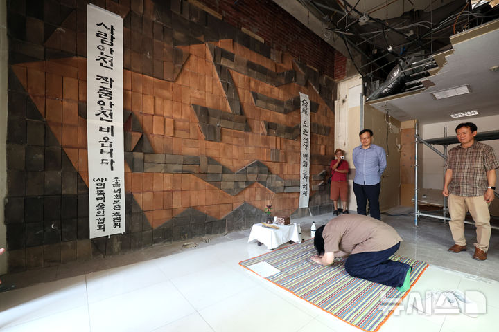 [서울=뉴시스] 박진희 기자 = 오상엽(오윤의 차남) 추진위원회 운영위원이 3일 서울 광진구 구의동 옛 상업은행(현 우리은행) 지점 건물 내 오윤의 테라코타 벽화 앞에서 오윤 구의동 테라코타 보존 추진위원회와 사단법인 한국민족미술인협회 공동으로 마련한 '오윤 테라코타 무사해체 기원제'에 참석하여 절을 하고 있다.  이 벽화는 한국 민중미술의 선구자 오윤(1946~1986)이 1973년 동료 오경환, 윤광주와 함께 제작한 테라코타 부조다. 오윤은 소설가 오영수의 장남으로, '현실동인'과 '현실과 발언' 등의 활동을 한 1980년대 민중미술 대표 작가다. 2026.08.03. pak7130@newsis.com