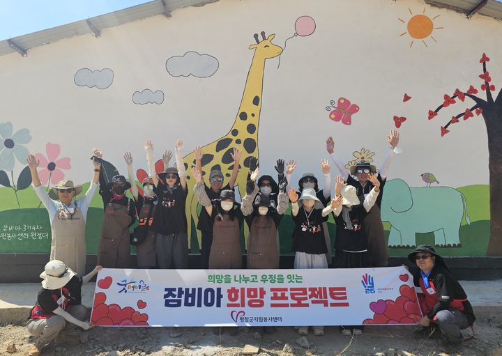 [평창=뉴시스] 평창군가족봉사단이 잠비아 희망 프로젝트를 통해 완성한 학교 벽화 앞에서 현지 주민들과 기념촬영을 하고 있다. (사진=평창군 제공) 2026.08.06. photo@newsis.com *재판매 및 DB 금지