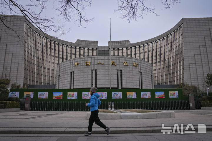 [베이징=AP/뉴시스] 2024년 2월20일 중국 베이징의 중국인민은행 앞을 한 여성이 달리고 있다. 2024.02.20.