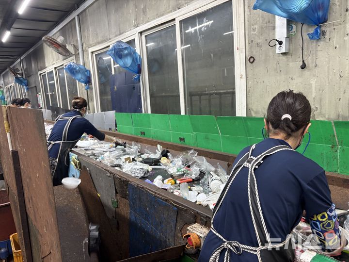 [서울=뉴시스] 신유림 기자 = 지난 7일 오후 경기도의 한 자원순환센터 선별실에서 선별원들이 컨베이어벨트를 따라 이동하는 재활용품을 손으로 골라내고 있다. 벽면에는 더위를 식히기 위한 선풍기가 여러 대 설치돼 있다. 2026.08.10. spicy@newsis.com