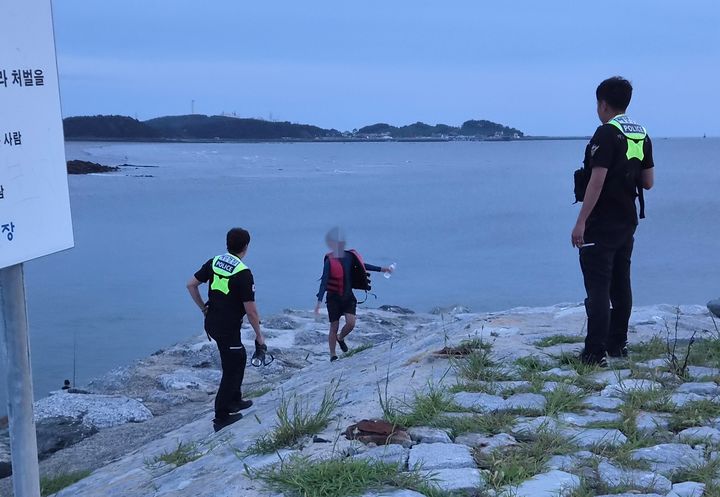 [보령=뉴시스] 지난 10일 오후 일행과 함께 갯벌에 나갔다 홀로 떨어져 바다를 표류하던 10대가 때마침 인근을 지나던 어선에 의해 구조된 뒤 서천 부사방조제에 내려 해경을 만나고 있다. (사진=보령해양경찰서 제공) 2026.08.11. photo@newsis.com *재판매 및 DB 금지
