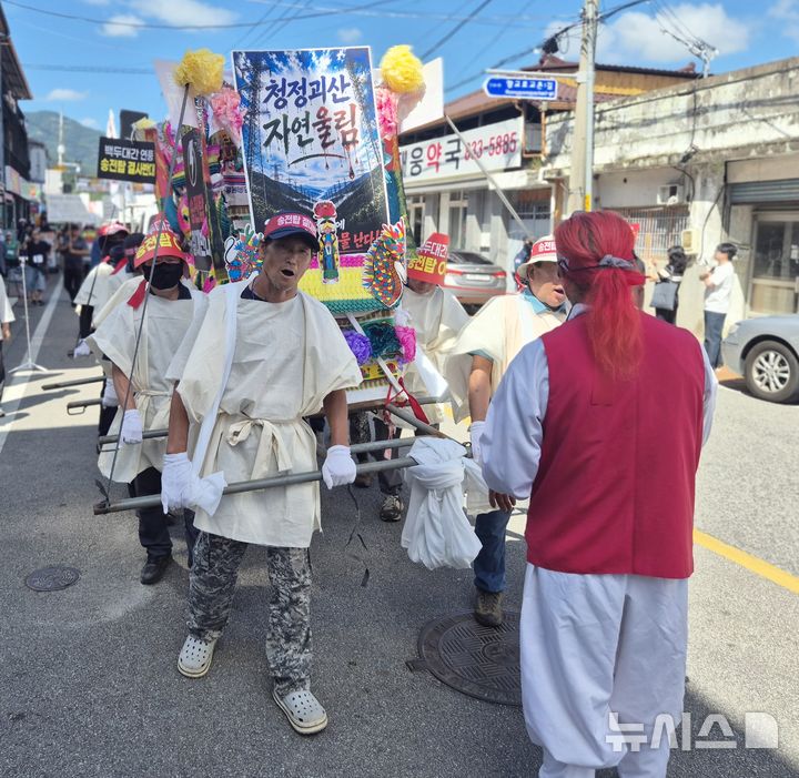 [괴산=뉴시스] 서주영 기자 = 충북 괴산군 연풍면 주민들이 12일 연풍 전통시장 일대에서 열린 송전탑 건설 반대 궐기대회에서 꽃상여를 메고 행진하고 있다. 주민들은 백두대간을 지나는 345㎸ 초고압 송전선로 건설계획의 중단과 경과지 재검토를 촉구했다. 2026.08.12. juyeong@newsis.com *재판매 및 DB 금지