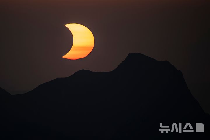 [베른=AP/뉴시스] 12일(현지 시간) 스위스 베른고원 니젠산 정상에서 바라본 부분일식 동안 달이 간트리슈산 정상 위로 태양을 가리고 있다.