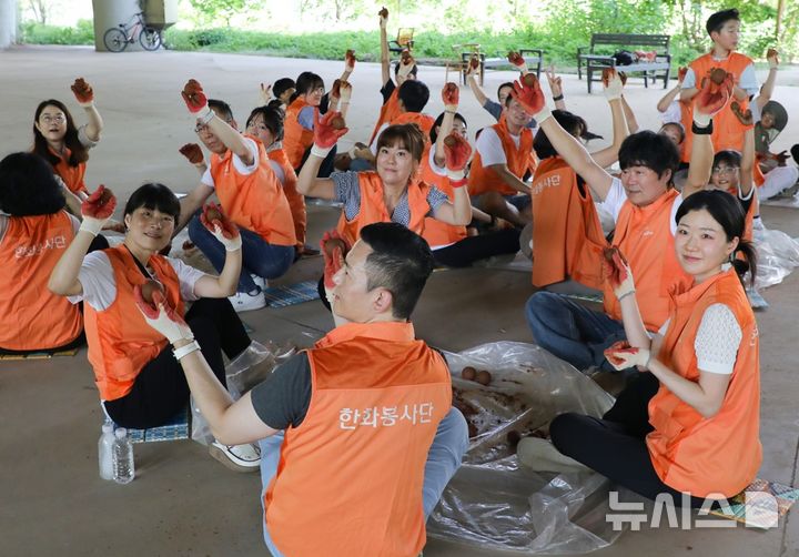[서울=뉴시스]한화투자증권 임직원들이 지난 6일 서을 여의도샛강생태공원에서 EM 흙공을 만들고 있다. (사진=한화투자증권 제공) 2026.08.13. photo@newsis.com 