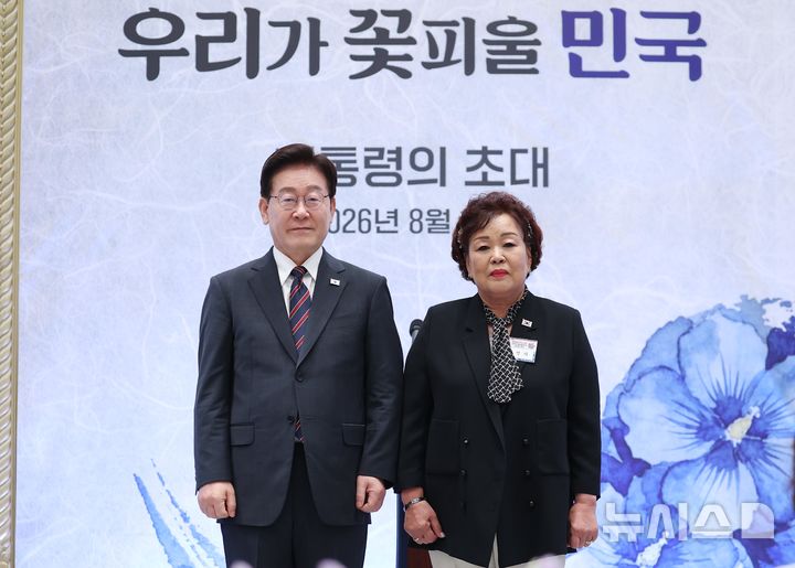 [서울=뉴시스] 조성봉 기자 = 이재명 대통령이 13일 청와대 영빈관에서 열린 국가유공자 및 보훈 가족 초청 오찬 행사에서 5·18 유공자 고 정동년 선생 배우자 이명자 씨에게 태극기 배지를 증정하고 기념 촬영을 하고 있다. 2026.08.13. suncho21@newsis.com