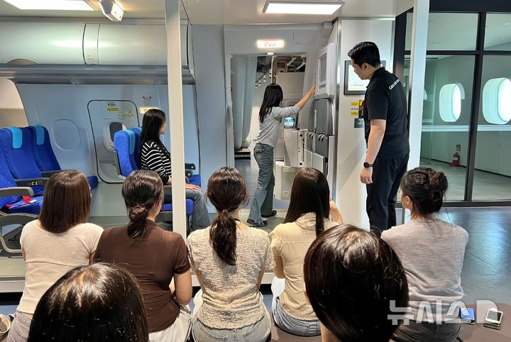 [부산=뉴시스] 원동화 기자 = 14일 오후 부산 강서구에 위치한 에어부산 본사 훈련시설에서 '시민 항공안전 체험 교육'에 참여한 참가자가 항공기 문을 실제로 열어보고 있다. 2026.08.14. dhwon@newsis.com