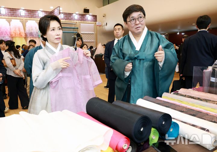 [서울=뉴시스] 조성봉 기자 = 김혜경 여사가 14일 서울 동대문디자인플라자(DDP)에서 열린 2026 한복상점 전시회에서 최휘영 문화체육관광부 장관과 원단을 살펴보고 있다. (청와대통신사진기자단) 2026.08.14. suncho21@newsis.com