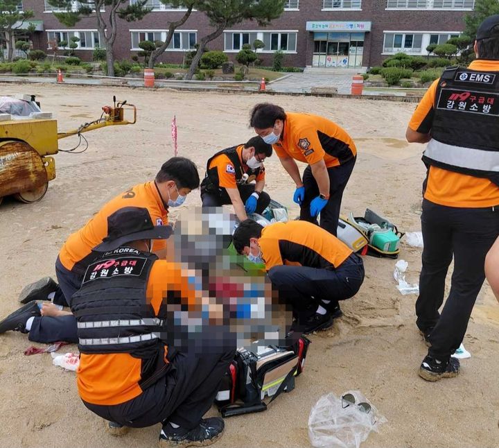[강릉=뉴시스] 15일 강원 강릉시 주문진읍 한 초등학교에서 배수로 작업 중이던 키르기스스탄 국적의 50대 A씨가 가슴 부위를 크게 다쳐 119구급대가 응급처치에 나서고 있다.(사진=강원도소방본부 제공)photo@newsis.com *재판매 및 DB 금지