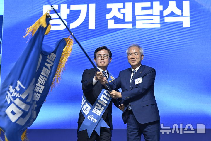 [나주=뉴시스] 양시원 기자 = 15일 오후 전남광주 나주시 종합스포츠파크 다목적체육관에서 열린 더불어민주당 전남광주통합특별시당 정기당원대회에서 초대 민주당 전남광주시당위원장으로 선출된 안도걸 당선인(왼쪽)과 양부남 의원이 시당기를 흔들고 있다. 2026.08.15. goodwrite97@newsis.com