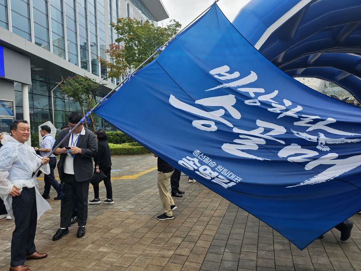 [대전=뉴시스]한재혁 기자 = 17일 송영길 더불어민주당 당대표 후보의 지지자가 대전 대전컨벤션센터에서 송영길 지지자 모임의 이름이 적힌 대형 깃발을 들고 있다. 2026.08.17. saebyeok@newsis.com *재판매 및 DB 금지