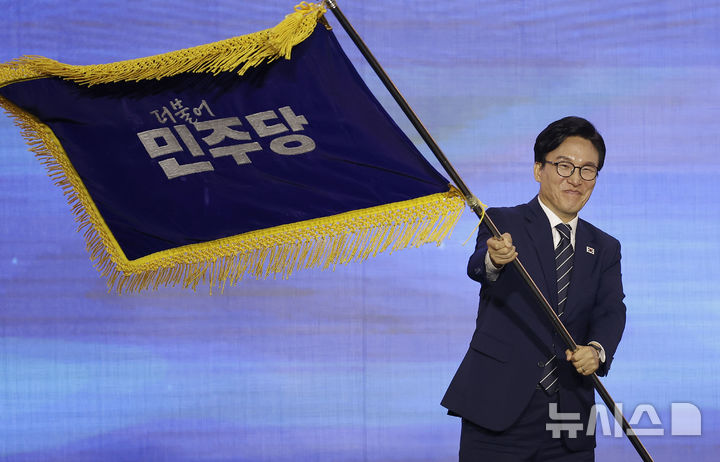 [대전=뉴시스] 정병혁 기자 = 김민석 신임 더불어민주당 당대표가 17일 대전 유성구 대전컨벤션센터 제2전시장에서 열린 더불어민주당 제3차 정기전국당원대회에서 당기를 흔들고 있다. 2026.08.17. jhope@newsis.com