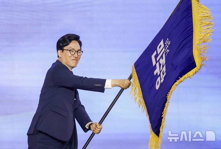 [대전=뉴시스] 정병혁 기자 = 김민석 신임 더불어민주당 당대표가 17일 대전 유성구 대전컨벤션센터 제2전시장에서 열린 더불어민주당 제3차 정기전국당원대회에서 당기를 흔들고 있다. 2026.08.17. jhope@newsis.com