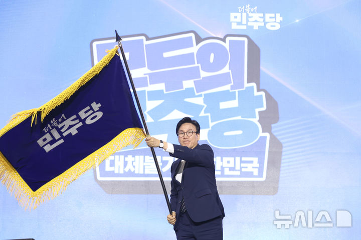 [대전=뉴시스] 정병혁 기자 = 김민석 신임 더불어민주당 당대표가 17일 대전 유성구 대전컨벤션센터 제2전시장에서 열린 더불어민주당 제3차 정기전국당원대회에서 당기를 흔들고 있다. (공동취재) 2026.08.17. photo@newsis.com