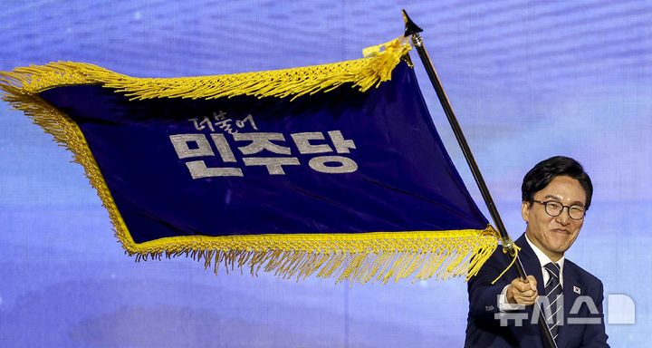 [대전=뉴시스] 정병혁 기자 = 김민석 신임 더불어민주당 당대표가 17일 대전 유성구 대전컨벤션센터 제2전시장에서 열린 더불어민주당 제3차 정기전국당원대회에서 당기를 흔들고 있다. 2026.08.17. jhope@newsis.com