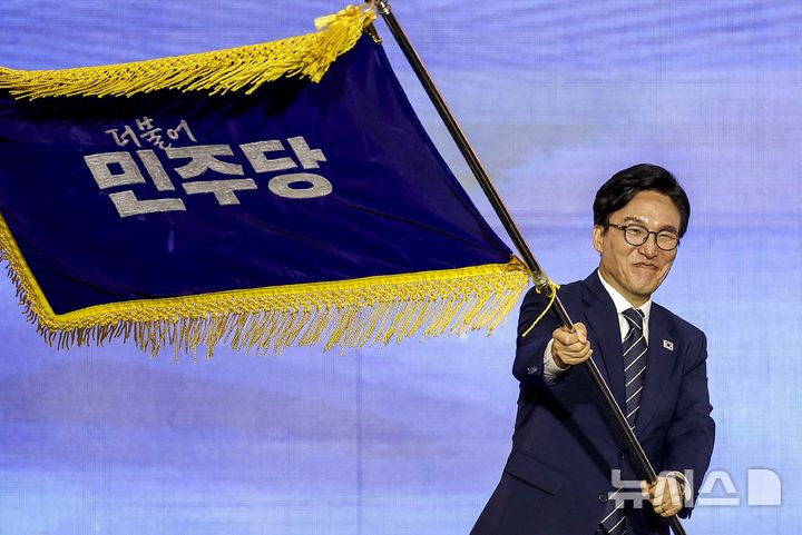 [대전=뉴시스] 정병혁 기자 = 김민석 신임 더불어민주당 당대표가 17일 대전 유성구 대전컨벤션센터 제2전시장에서 열린 더불어민주당 제3차 정기전국당원대회에서 당기를 흔들고 있다. 2026.08.17. jhope@newsis.com