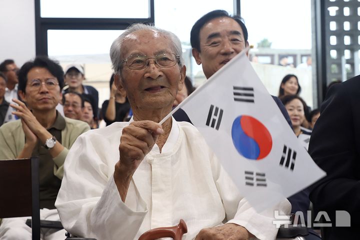 [서울=뉴시스] 광복잇길 행사에 참석한 강태선 애국지사가 태극기를 흔들고 있다. (사진= 자생한방병원 제공) 