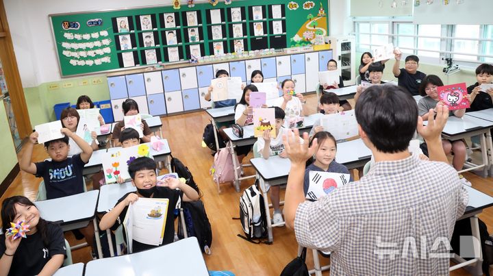  [부산=뉴시스] 하경민 기자 = 2026학년도 2학기 개학식이 열린 18일 부산 영도구 대평초등학교 4학년 2반 교실에서 학생들이 여름방학 과제를 들어보이며 교사와 인사하고 있다. 2026.08.18. yulnetphoto@newsis.com