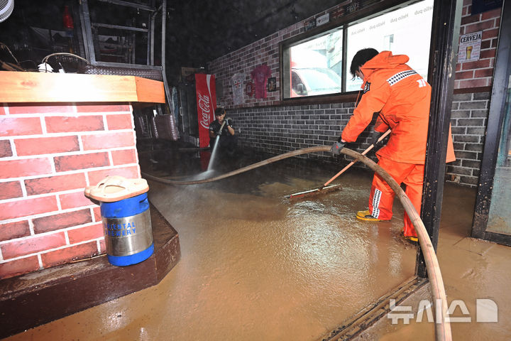 [거제=뉴시스] 차용현 기자 = 18일 오전 기록적인 폭우로 큰 피해가 발생한 경남 거제시 옥포동의 한 상가에서 거제소방서 정현덕·심지헌 소방관이 가게 주인을 도와 내부에 유입된 흙탕물을 제거하는 등 수해 복구 작업을 벌이고 있다. 2026.08.18. con@newsis.com