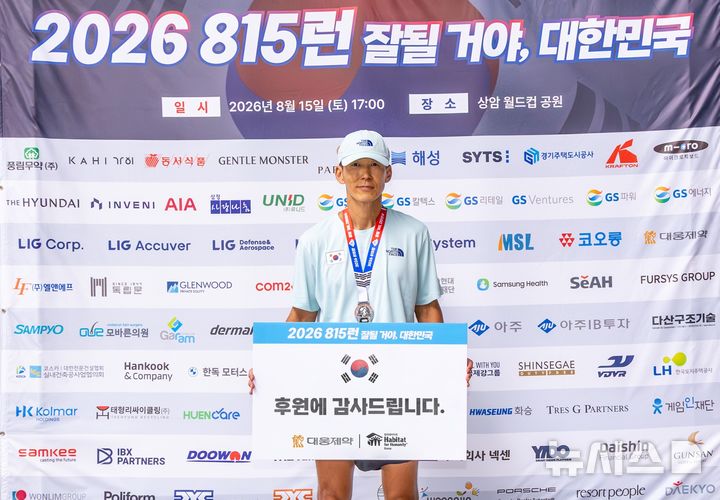 [서울=뉴시스] '2026 815런' 81.5㎞ 완주에 성공한 가수 션이 대웅제약의 후원 감사 보드를 들고 포토월에서 기념 촬영을 하고 있다. (사진=대웅제약 제공) 2026.08.20. photo@newsis.com