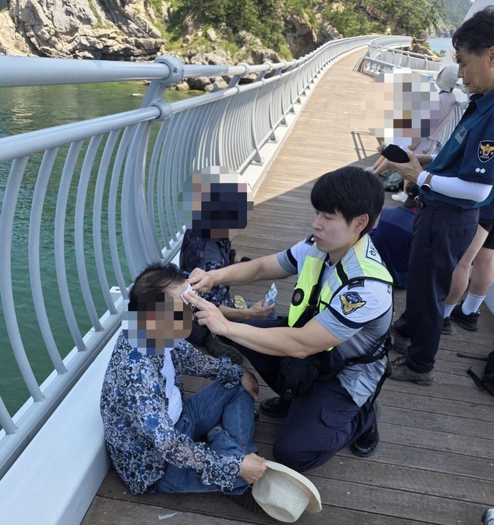 [군산=뉴시스] 25일 오전 11시께 해경이 온열질환 증세를 보이는 관광객에게 쿨링패치를 이용해 응급조치를 하고 있다. (사진=해경 제공) 2026.08.26. photo@newsis.com *재판매 및 DB 금지