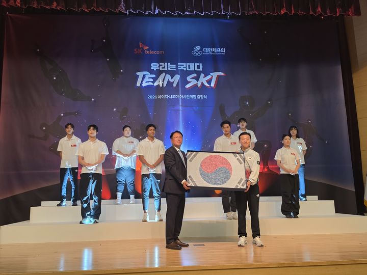 진천=뉴시스] 박은비 기자 = SK텔레콤이 충북 진천의 국가대표선수촌에서 '팀(Team) SKT' 출정식을 개최했다. 사진은 이날 행사에서 권영상 SK텔레콤 부사장이 '국민응원 태극기'를 이날 김택수 국가대표선수촌장에게 전달하는 모습. 2026.08.26. silverline@newsis.com *재판매 및 DB 금지