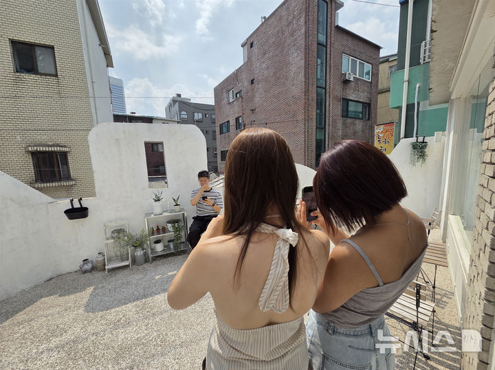 [서울=뉴시스]고선영 수습기자=카페 야외 테라스로 자리를 옮겨 사진 찍기를 이어가는 모습. 박모(19)씨와 최모(28)씨가 김모(27)씨의 사진을 찍어주고 있다. 2026.08.29. sunzero@newsis.com