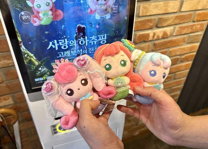[서울=뉴시스] 고객이 메가MGC커피 매장에서 지난달 출시한 '캐치 티니핑' 극장판 '사랑의 하츄핑: 고래보석의 전설' 공식 굿즈를 들어 보이고 있다. (사진=메가MGC커피 제공) *재판매 및 DB 금지