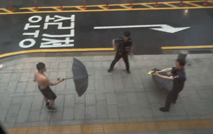 [서울=뉴시스]남성은 권투 자세로 주먹을 휘두르며 출동한 경찰관에게 폭력을 가하고, 우산으로 저항하고 있다. 사진 독자 제보 *재판매 및 DB 금지