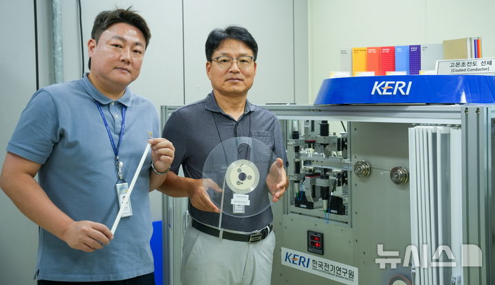 [창원=뉴시스]한국전기연구원 극저온기기연구센터 박인성(왼쪽)·하홍수 박사가 고온초전도 선재를 들고 3D 비접촉 초정밀 검사 장비 옆에서 포즈를 취하고 있다.(사진=한국전기연구원 제공) 2026.09.06. photo@newsis.com