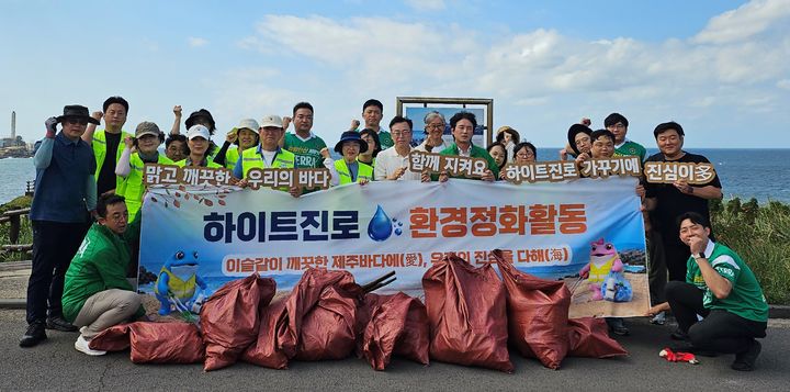 [서울=뉴시스] 9일 제주 닭머르해안에서 하이트진로 제주지점과 제주아라종합사회복지관, 폴리텍대학교 제주캠퍼스 교직원 및 대학생이 환경정화활동 행사에서 함께 기념촬영을 하고 있다. (사진=하이트진로 제공) *재판매 및 DB 금지