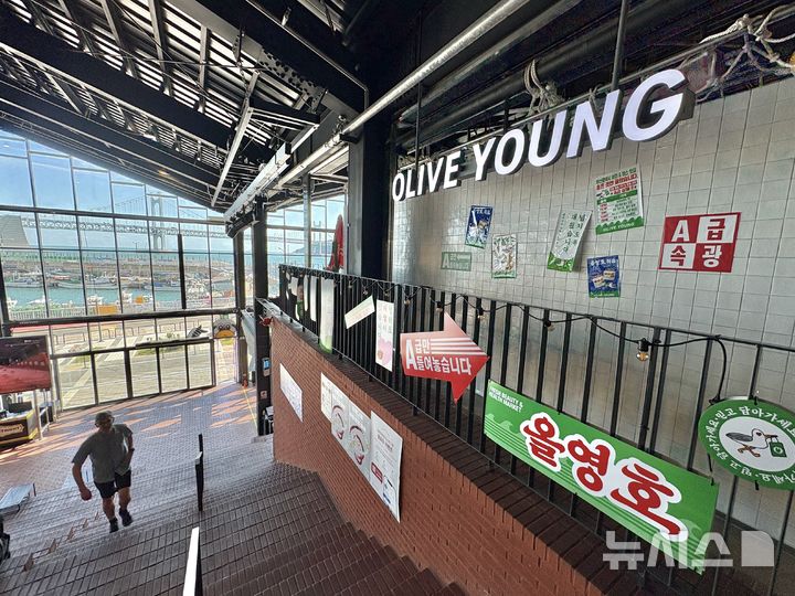 [부산=뉴시스] 권민지 기자 = 부산시 수영구 민락동 올리브영 밀락더마켓점. 민락항을 모티브로 한 간판과 포스터 등으로 꾸민 매장 통창 너머로 민락항이 보이고 있다. 2026.09.14. ming@newsis.com