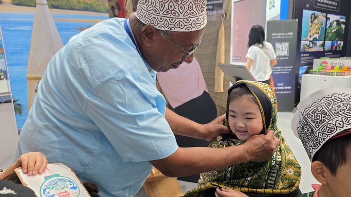 [여수=뉴시스] 2026여수세계섬박람회 주행사장 '국제교류섬'을 찾은 어린이가 케냐 전통 의상을 입어보는 현지 문화 체험을 하고 있다. (사진=조직위 제공) 2026.09.13. photo@newsis.com *재판매 및 DB 금지