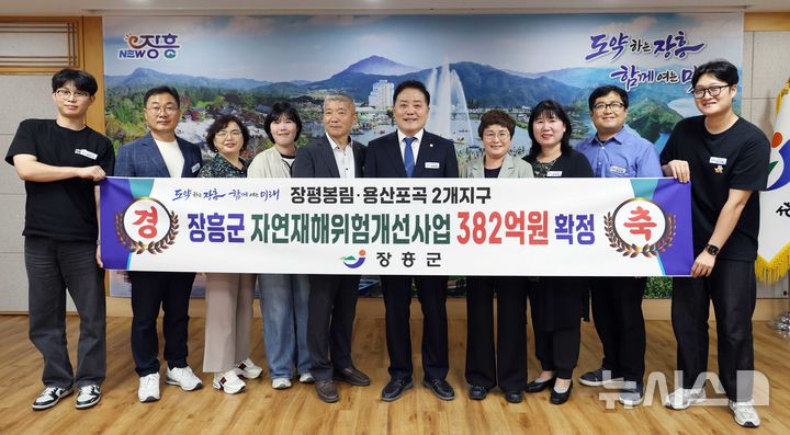 [장흥=뉴시스] 사순문 장흥군수(오른쪽 다섯 번째)가 청사에서 직원들과 함께 행정안전부의 2027년 자연재해예방 신규사업 2개 지구 선정에 따른 축하 현수막 앞에서 기념촬영을 하고 있다. (사진=장흥군 제공) photo@newsis.com *재판매 및 DB 금지