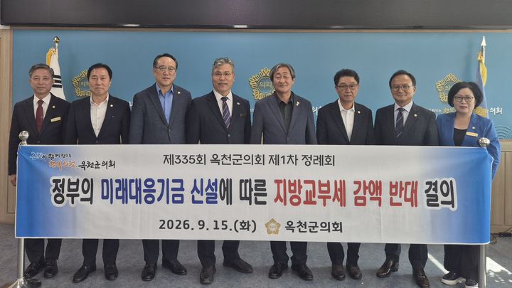 [옥천=뉴시스] 안효익(왼쪽 네번째) 의장 등 충북 옥천군의회 의원들이 15일 335회 1차 정례회 2차 본회의를 마친 후 본회의장에서 이용수 의원이 대표 발의한 '정부의 미래대응기금 신설에 따른 지방교부세 감액 반대 결의안'을 채택하고 카메라 앞에서 플래카드를 들어보이고 있다. (사진=옥천군의회 제공) 2026.09.15. photo@newsis.com *재판매 및 DB 금지