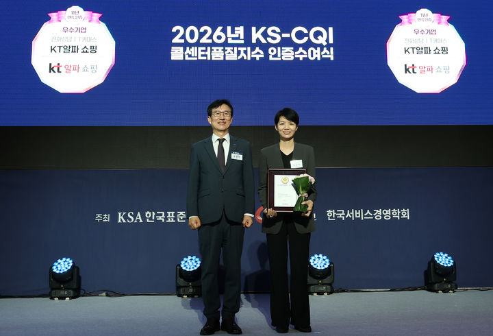 [서울=뉴시스] KT알파 쇼핑이 지난 15일 시그니엘 서울에서 진행된 ‘2026 콜센터품질지수(KS-CQI)’ 인증 수여식에서 업계 최초 11년 연속 최고점과 함께 인증을 획득했다. KT알파 쇼핑 백선주 T커머스사업부문장(오른쪽)이 한국표준협회 문동민 회장으로부터 인증패를 받은 모습.(사진=KT알파 제공) *재판매 및 DB 금지 *재판매 및 DB 금지