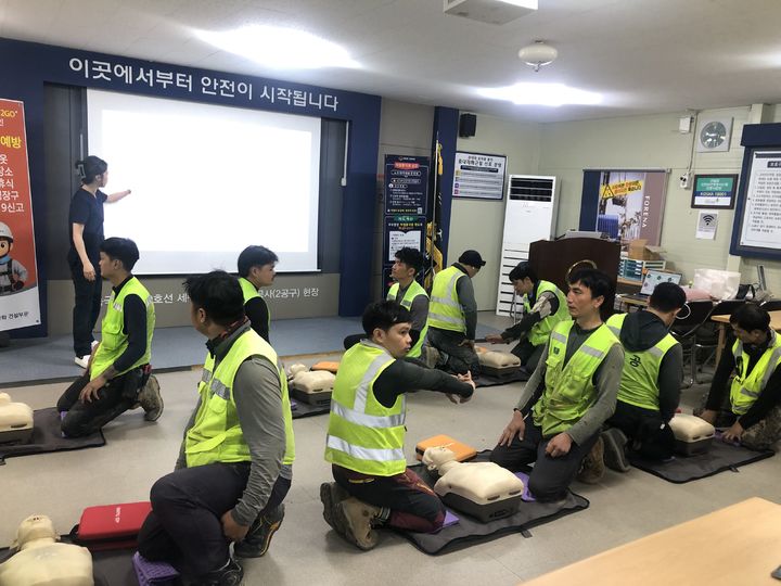 [서울=뉴시스] 한화 건설부문이 지난 16일 한화포레나 천안아산역 공사현장에서 실시한 '외국인 근로자 맞춤형 안전보건 교육'에 참여한 외국인 노동자들이 자동심장충격기(AED)를 사용해 실습하는 모습. (사진=한화 건설부문 제공) 2026.09.18. photo@newsis.com *재판매 및 DB 금지