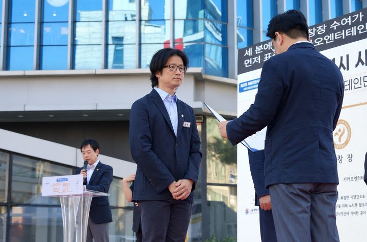 [서울=뉴시스] 카카오엔터테인먼트는 지난 19일 열린 '제21회 서울특별시수어문화제' 기념식에서 문화 향유권 증진과 장애인 인식 개선 공로로 서울특별시장 표창을 받았다고 21일 밝혔다. 사진은 이호준 카카오엔터테인먼트 대외법무총괄(가운데)이 상을 받는 모습. 2026.09.21. (사진=카카오엔터테인먼트 제공) *재판매 및 DB 금지