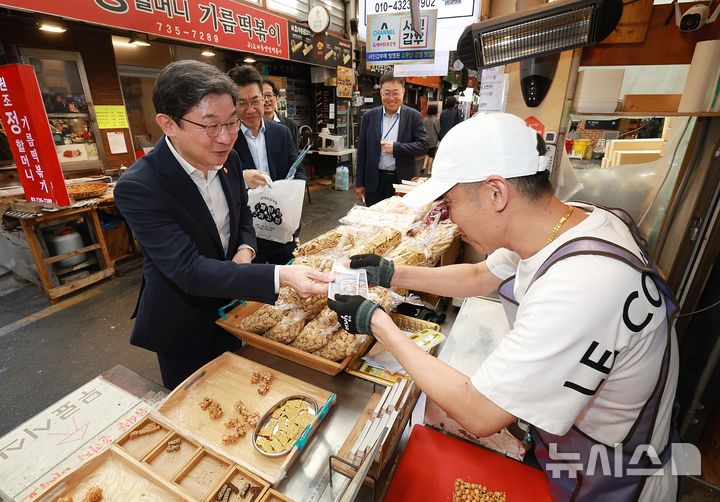 [서울=뉴시스] 이억원 금융위원장이 추석 명절을 앞둔 21일 오후 서울 종로구 통인시장에 방문해 고기, 한과, 송편 등을 구입하며, 시장상인들로부터 최근 전통시장 경기와 애로사항을 청취했다.(사진제공=금융위원회) 2026.09.21. photo@newsis.com