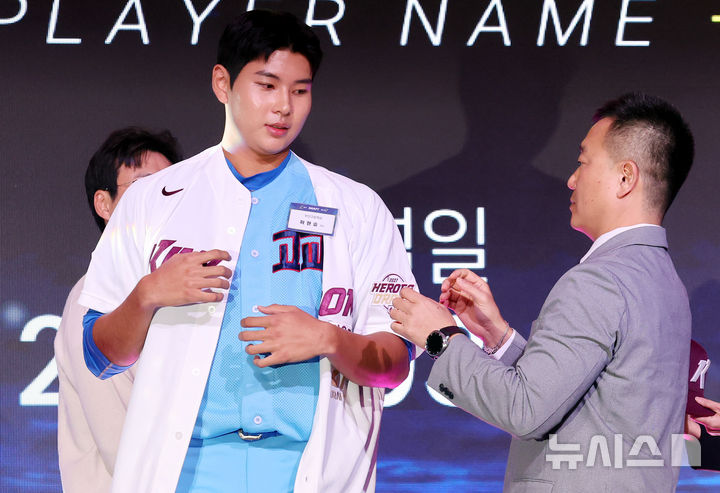[서울=뉴시스] 박영태 기자 = 21일 오후 서울 송파구 롯데호텔 월드 크리스탈볼룸에서 열린 2027 KBO 신인 드래프트, 전체 1순위 지명권을 보유한 키움 허승필 단장이 부산고 좌완투수 하현승을 지명한 후 유니폼을 입혀주고 있다. 2026.09.21. since1999@newsis.com